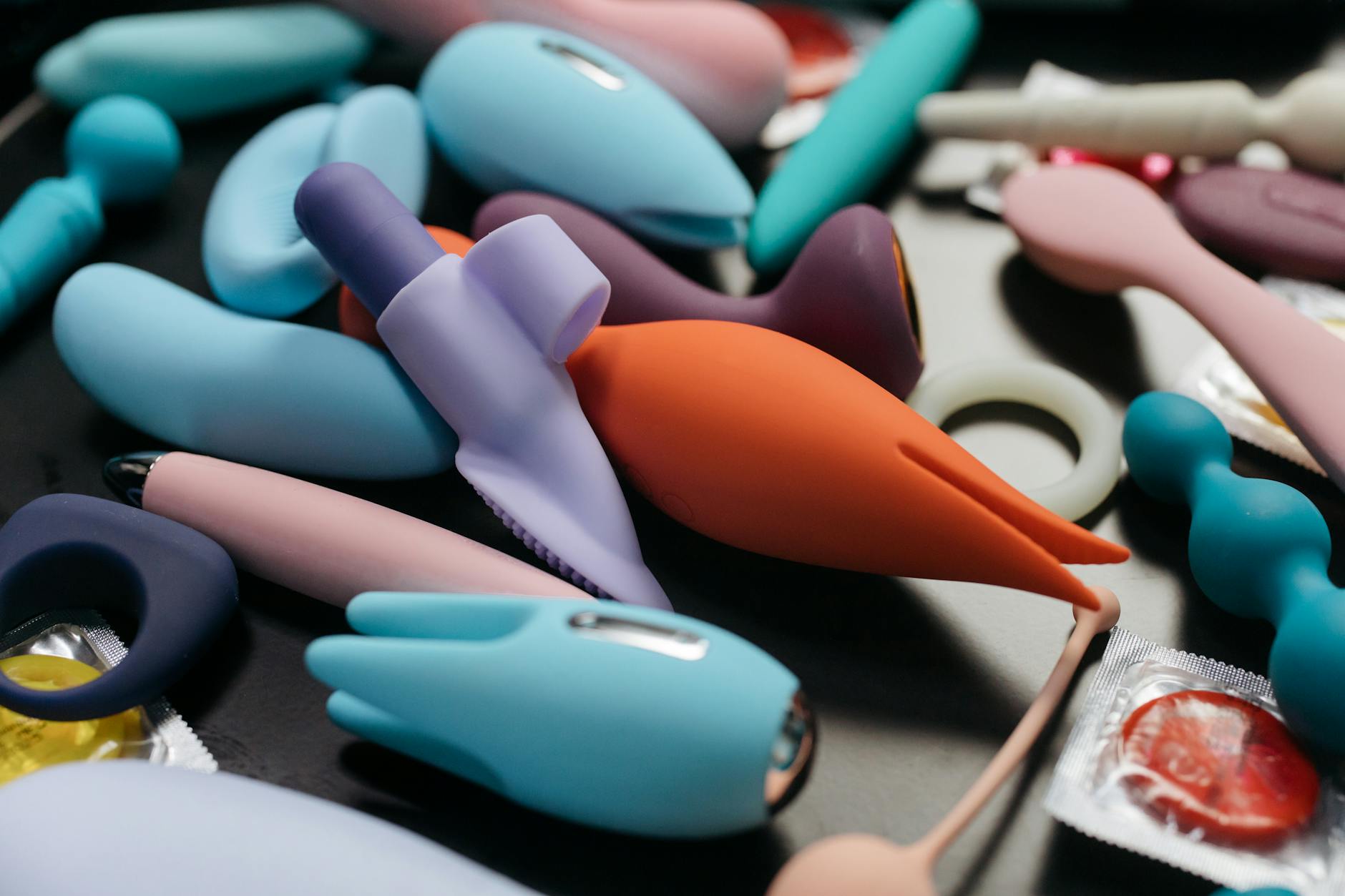 Close-up of a hand holding a vibrator with art books in the soft background, conveying intimate personal moments