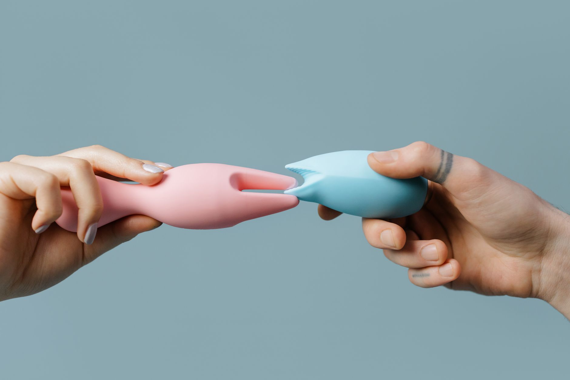 Hands holding a blue clitoral vibrator, a tool for reconnecting with bodily sensation