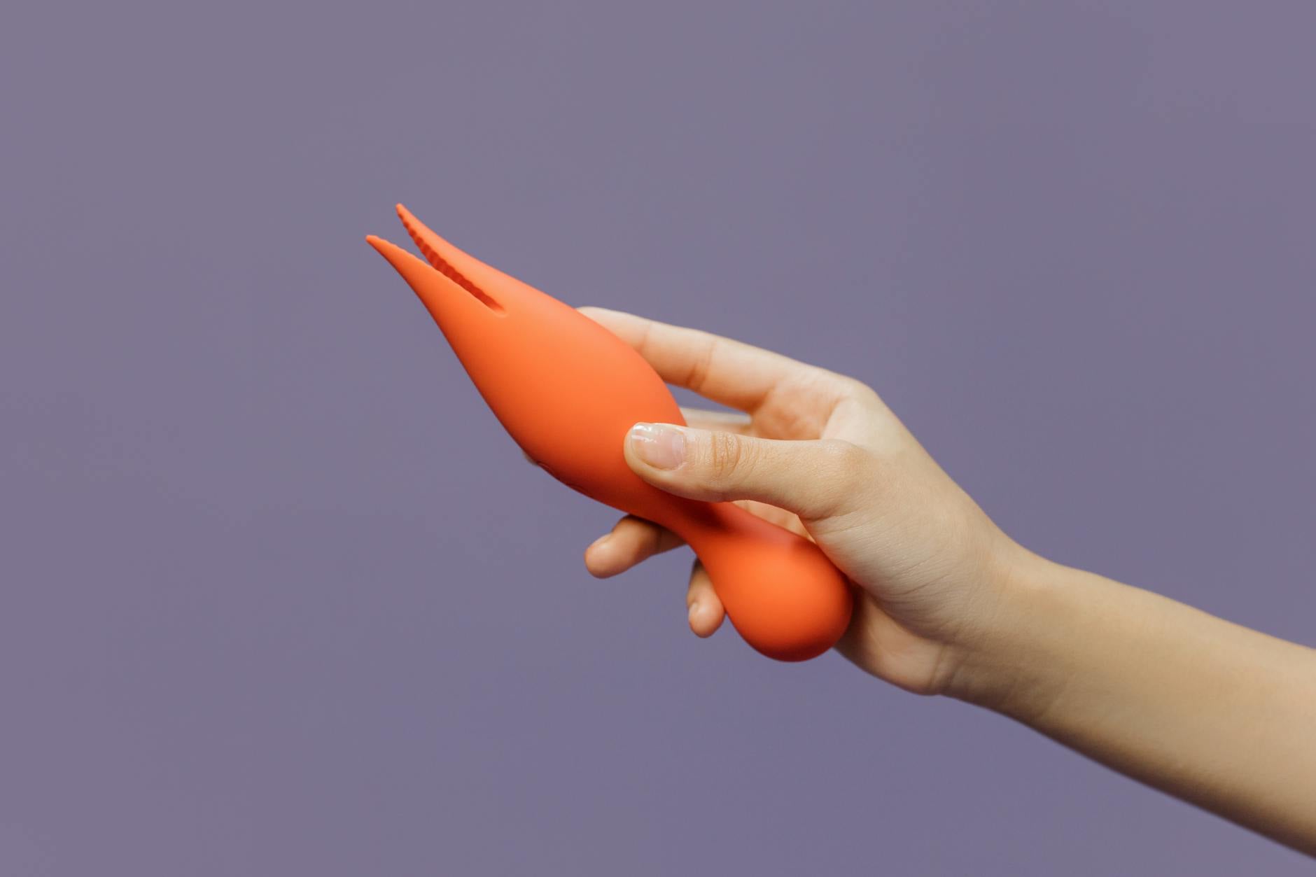 A close-up of a hand holding a lemon vibrator against a minimalistic purple backdrop, showcasing modern sensuality.