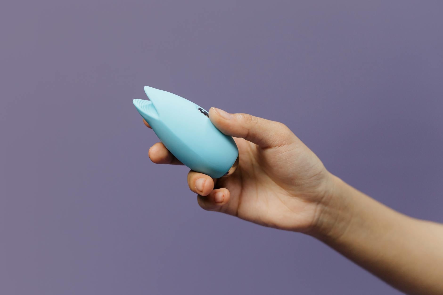 Close-up of a blue silicone vibrator held gently in hand