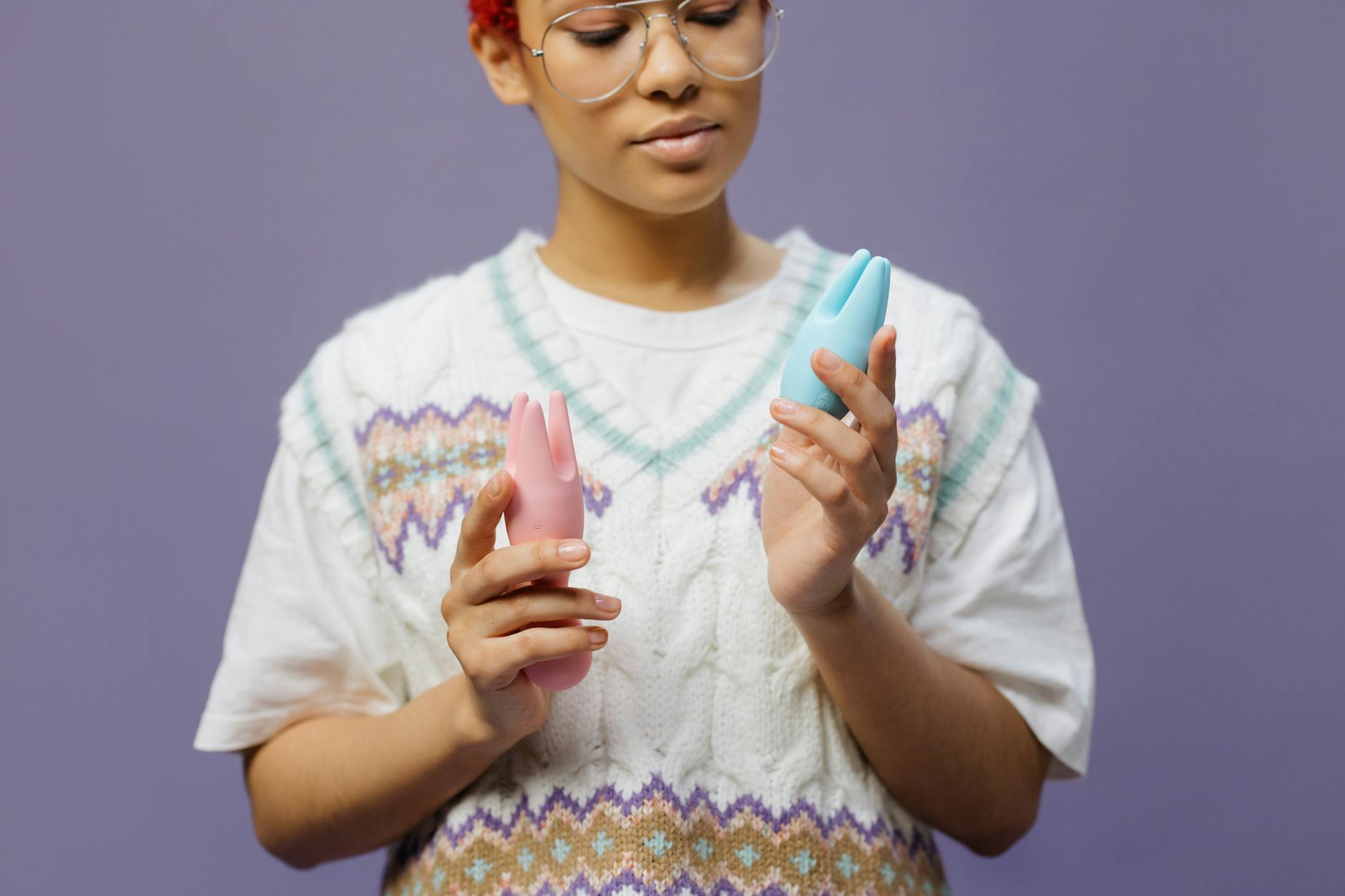 Woman holding blue and pink silicone vibrators, exploring reconnection with pleasure