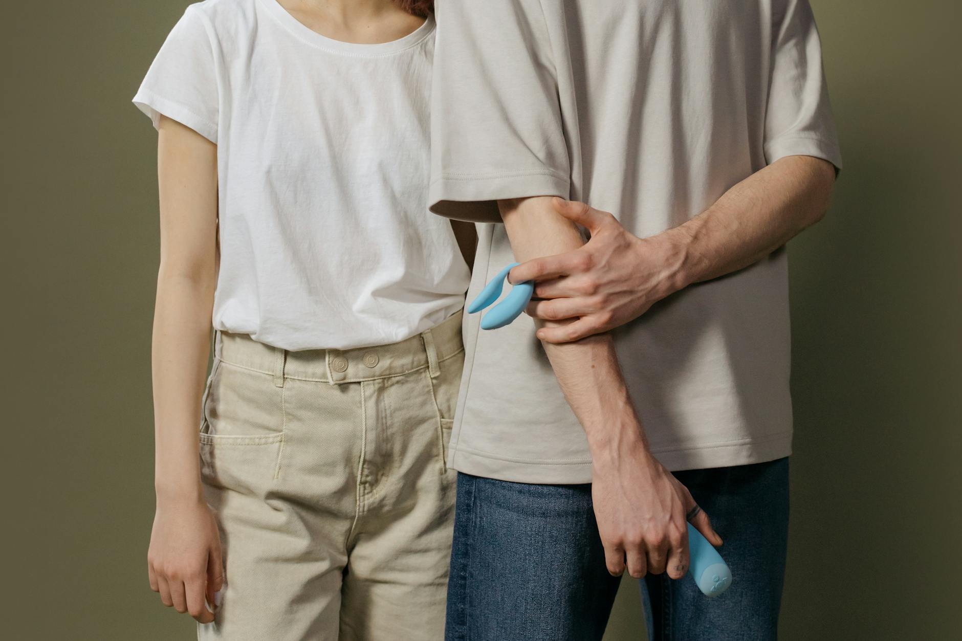 A young couple holding a blue vibrator together, symbolizing modern shared intimacy and communication.