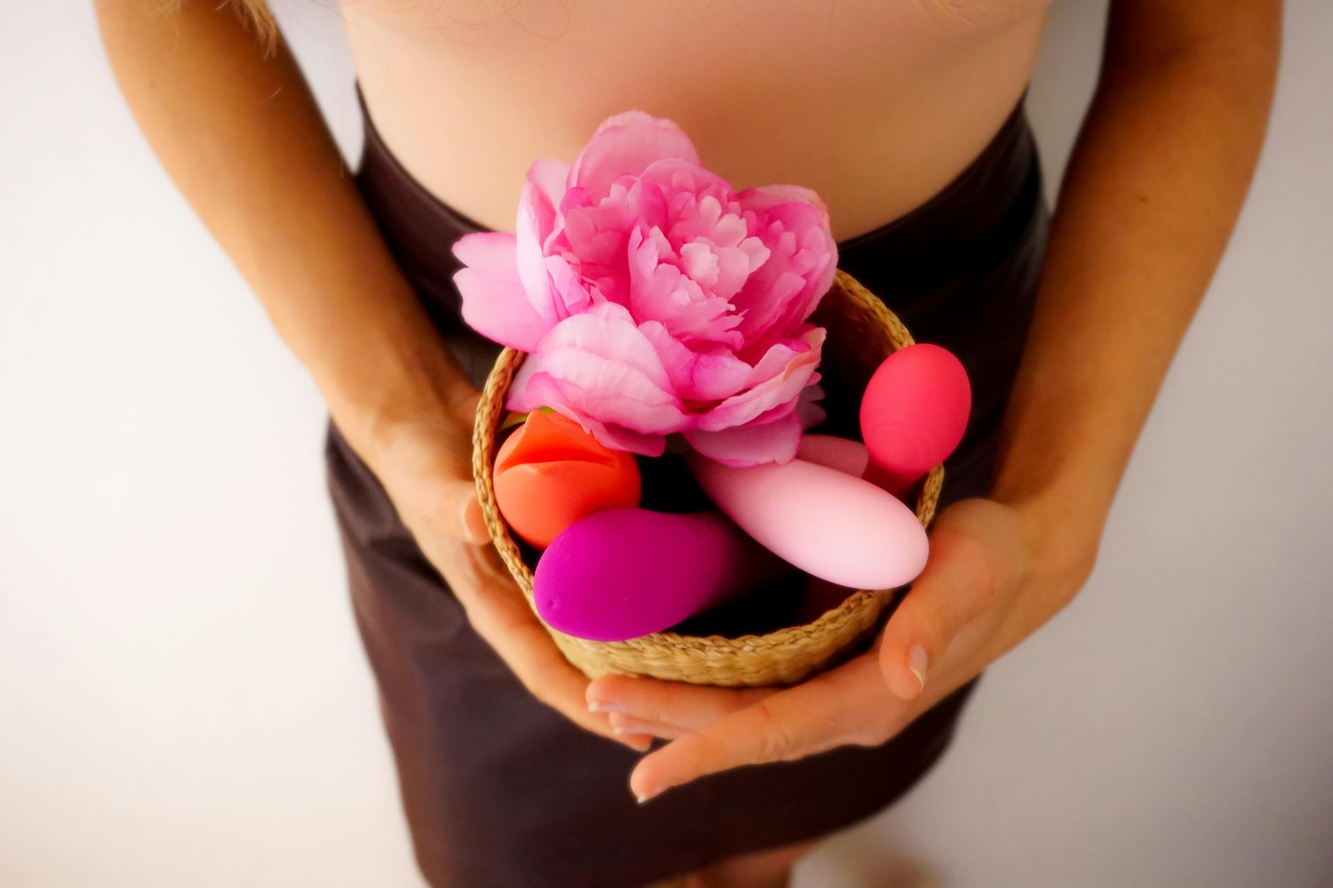 A basket of colorful vibrators and pleasure toys arranged with fresh flowers and natural accents